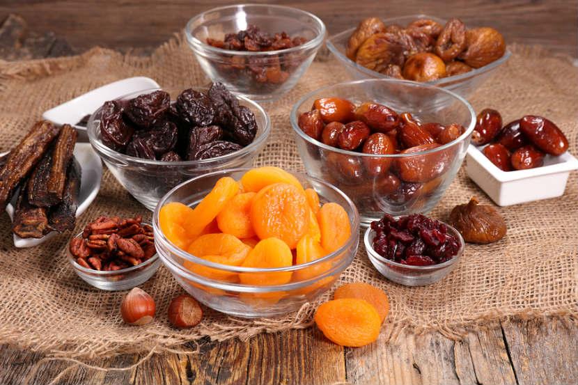Two hands holding a small bowl of mixed dried fruit